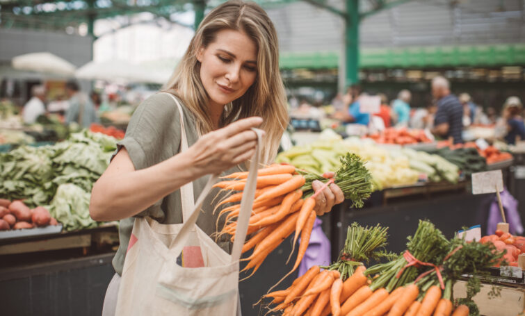 cheerful woman selecting fresh vegetables in market