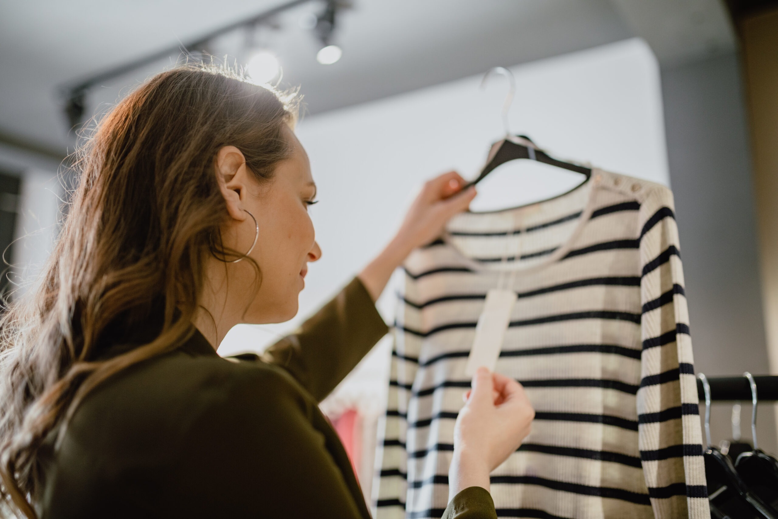 Young woman holding a clothing item and looking in the price tag in the clothing store
